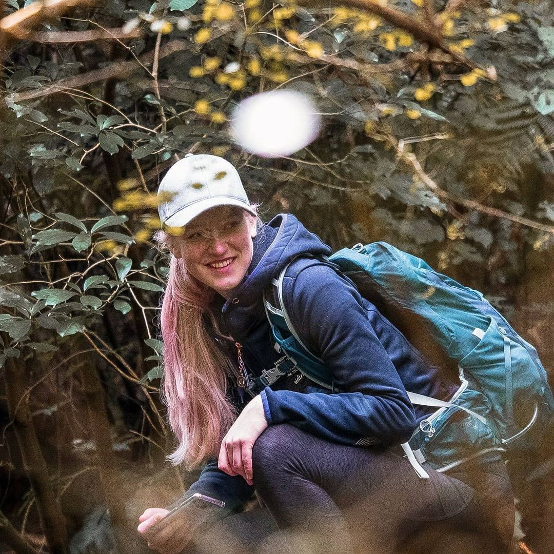 Instagram photo of Claudia sitting on a rock in a forest